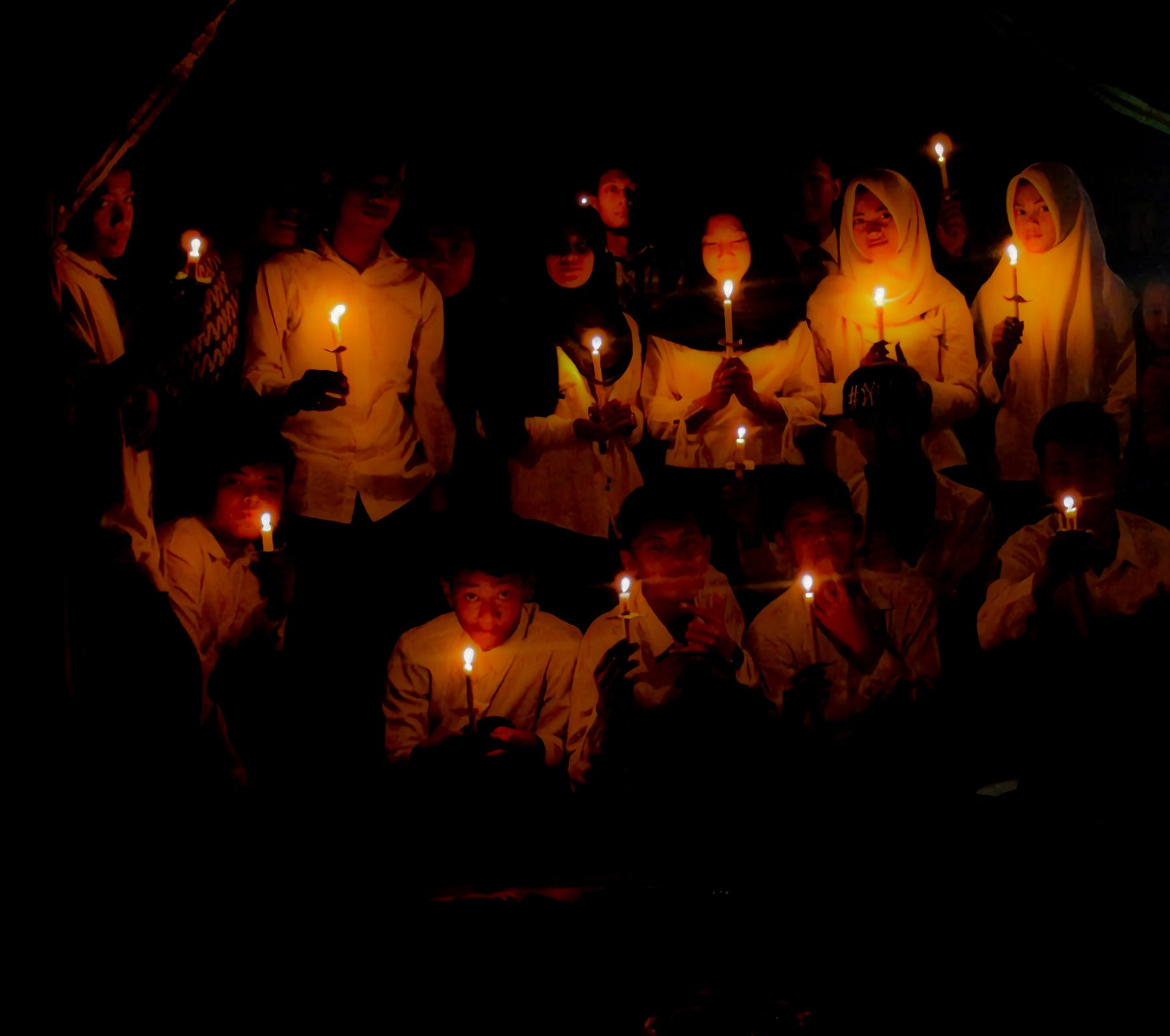 People holding candles in the dark.