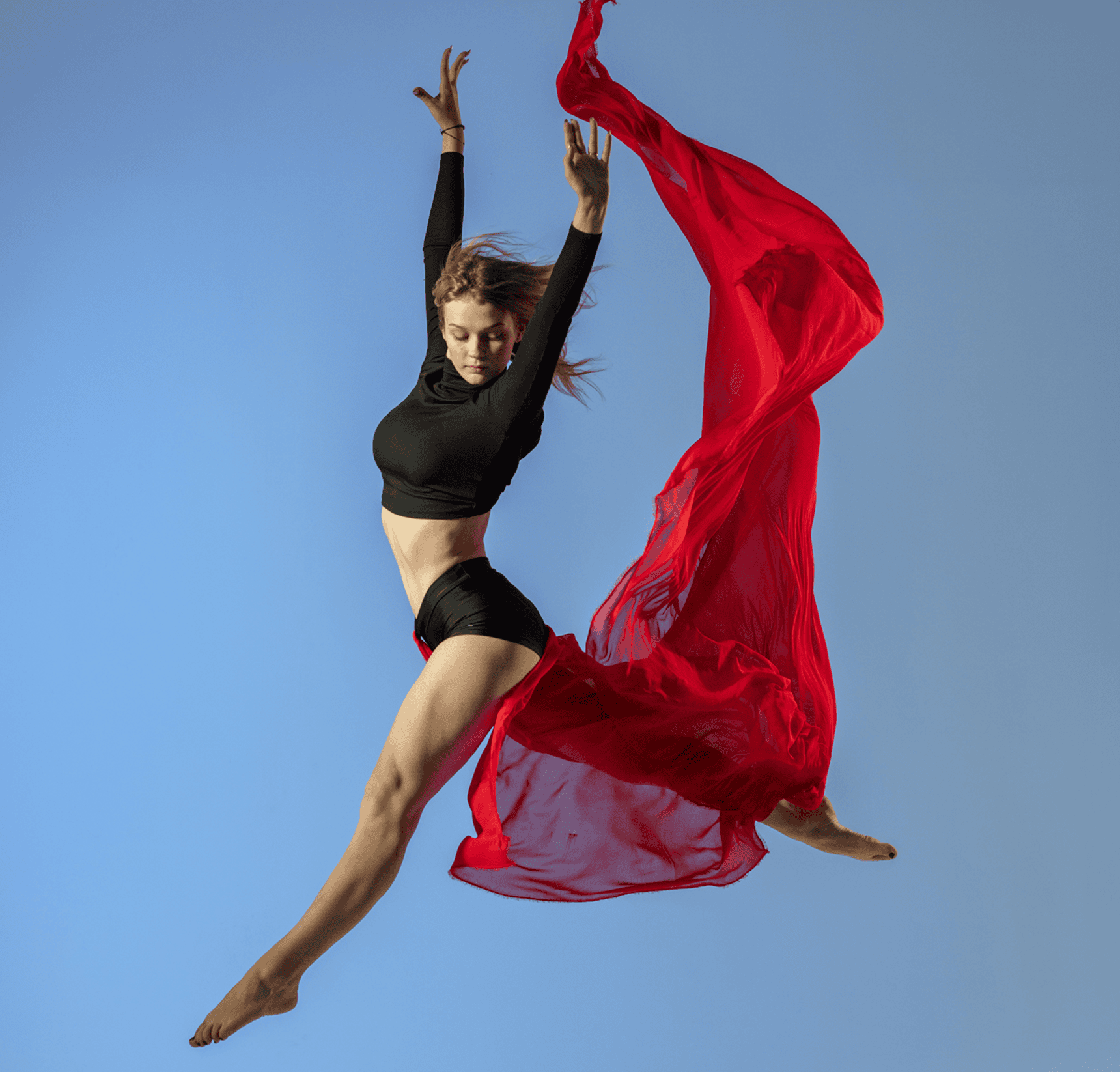 Dancer leaping with flowing red fabric.