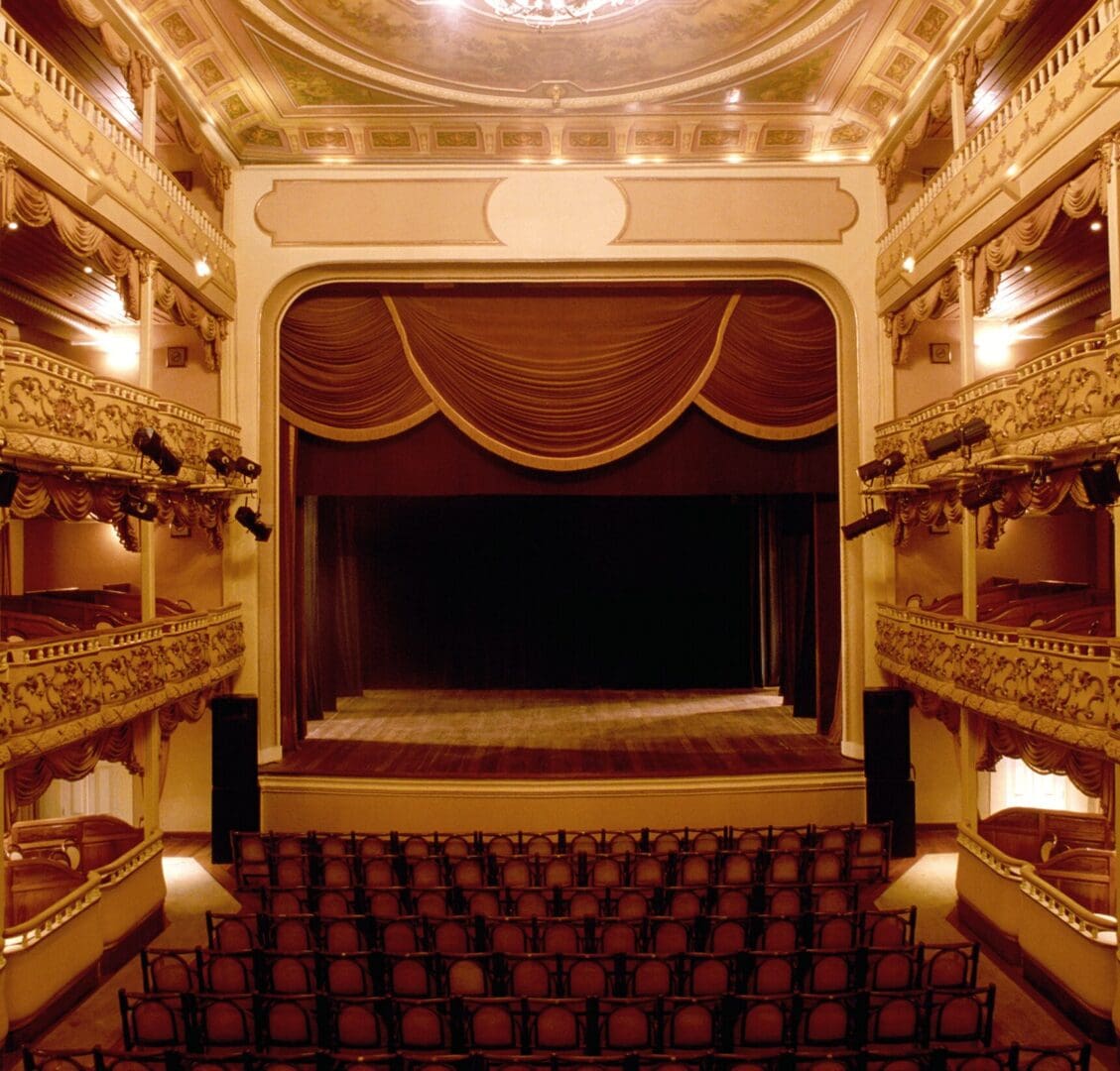 Ornate theater interior with empty stage and seats.