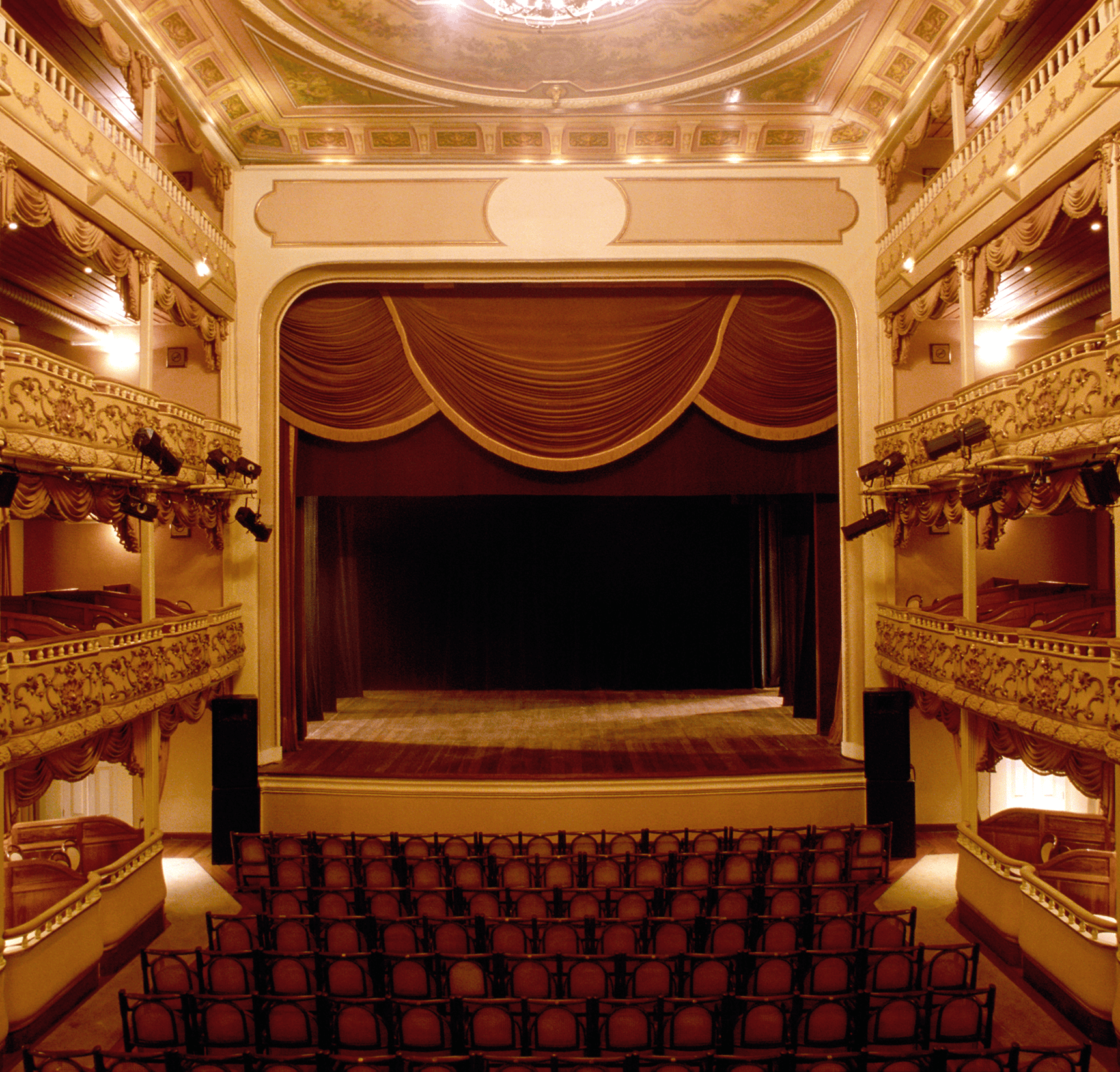 Ornate theater interior with empty stage and seats.